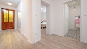 A hallway with wooden flooring, white walls, and a wooden door with glass panels. - Beachfront apartments Nincevic (Trogir)