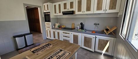 A kitchen with white cabinets, a countertop, and a dining table with placemats.