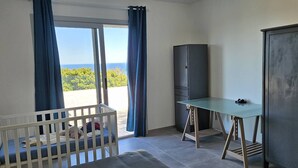 A room with a crib, a desk, a cabinet, and a view of the outdoors. - BELLA VISTA-WIFI-PANORAMIC SEA VIEW (SARI SOLENZARA)