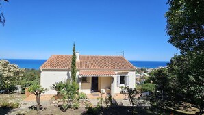 A white building with a red-tiled roof, a small porch, and a view of the sea. - BELLA VISTA-WIFI-PANORAMIC SEA VIEW (SARI SOLENZARA)