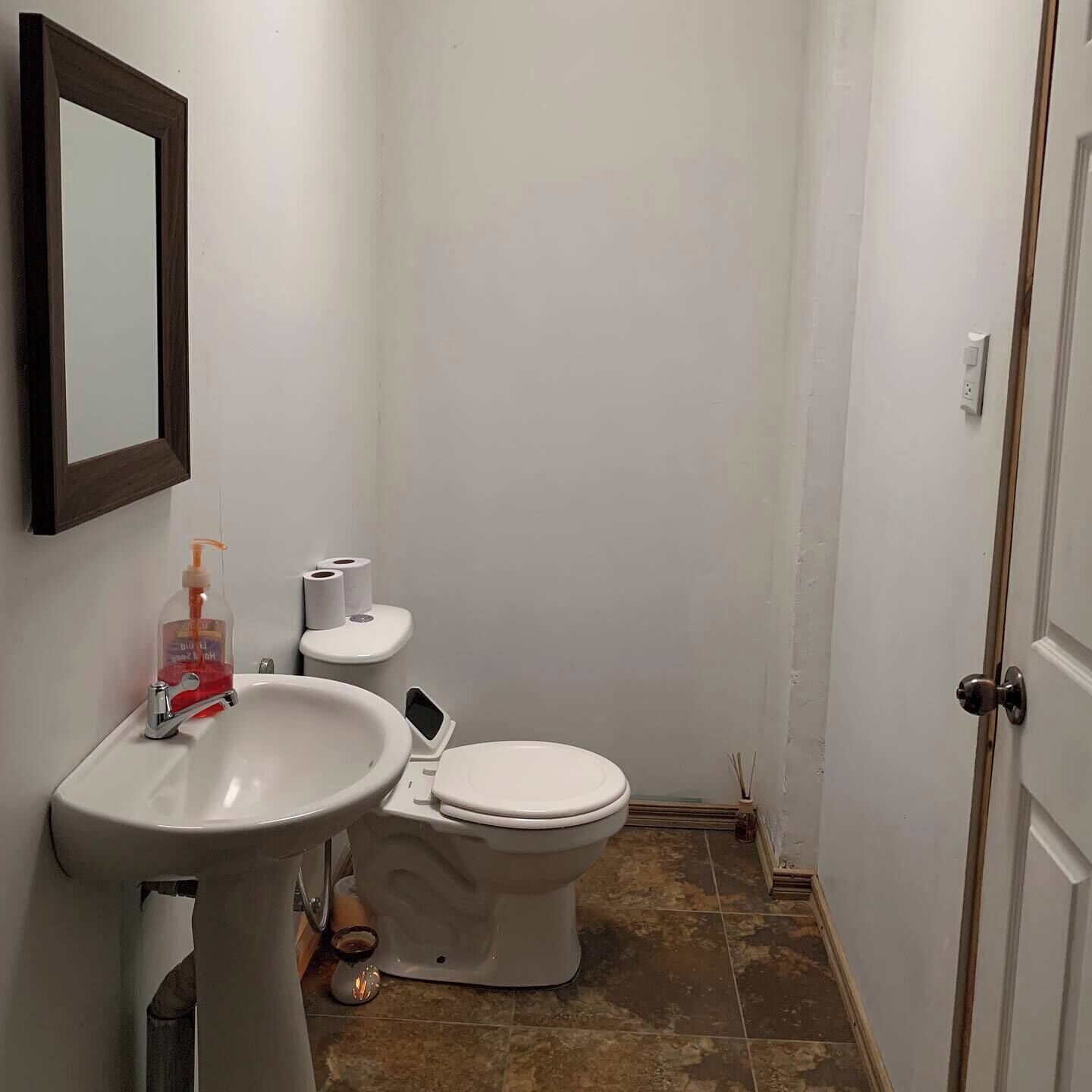 Un baño pequeño con inodoro y lavamanos blancos, y un espejo en la pared.