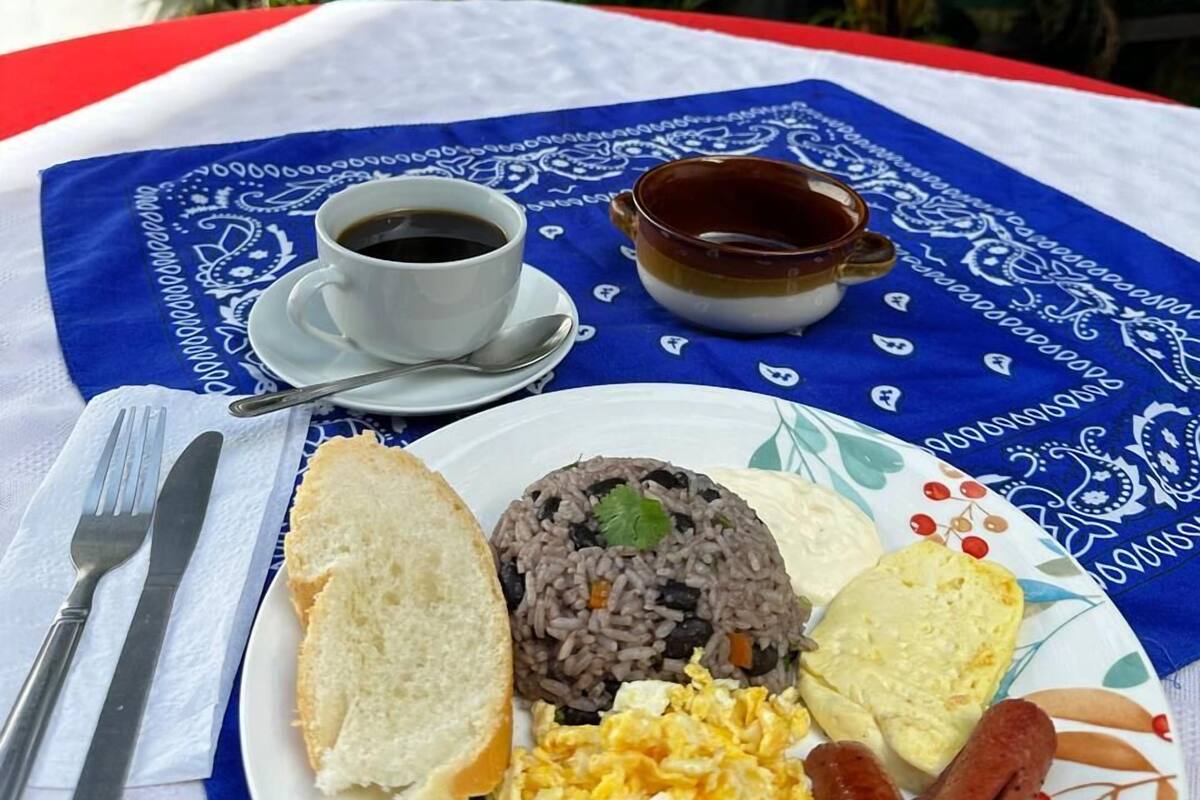 Lautasella on riisiä, munia, makkaroita ja leipää, ja pöydällä, jonka päällä on sininen pöytäliina, on myös kuppi kahvia ja kulho keittoa.