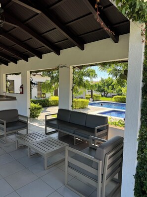 Ein Außenbereich mit Terrasse, Pool, einer Couch und einem Tisch.