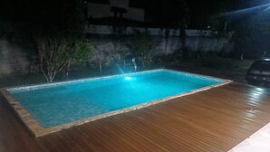 Ein rechteckiger Swimmingpool mit einer umlaufenden Holzterrasse.