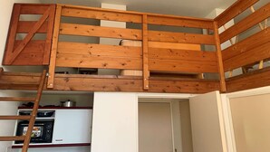 Ein Schlafzimmer im Loft-Stil mit einer Holzleiter, die zu einer erhöhten Zwischenebene führt.