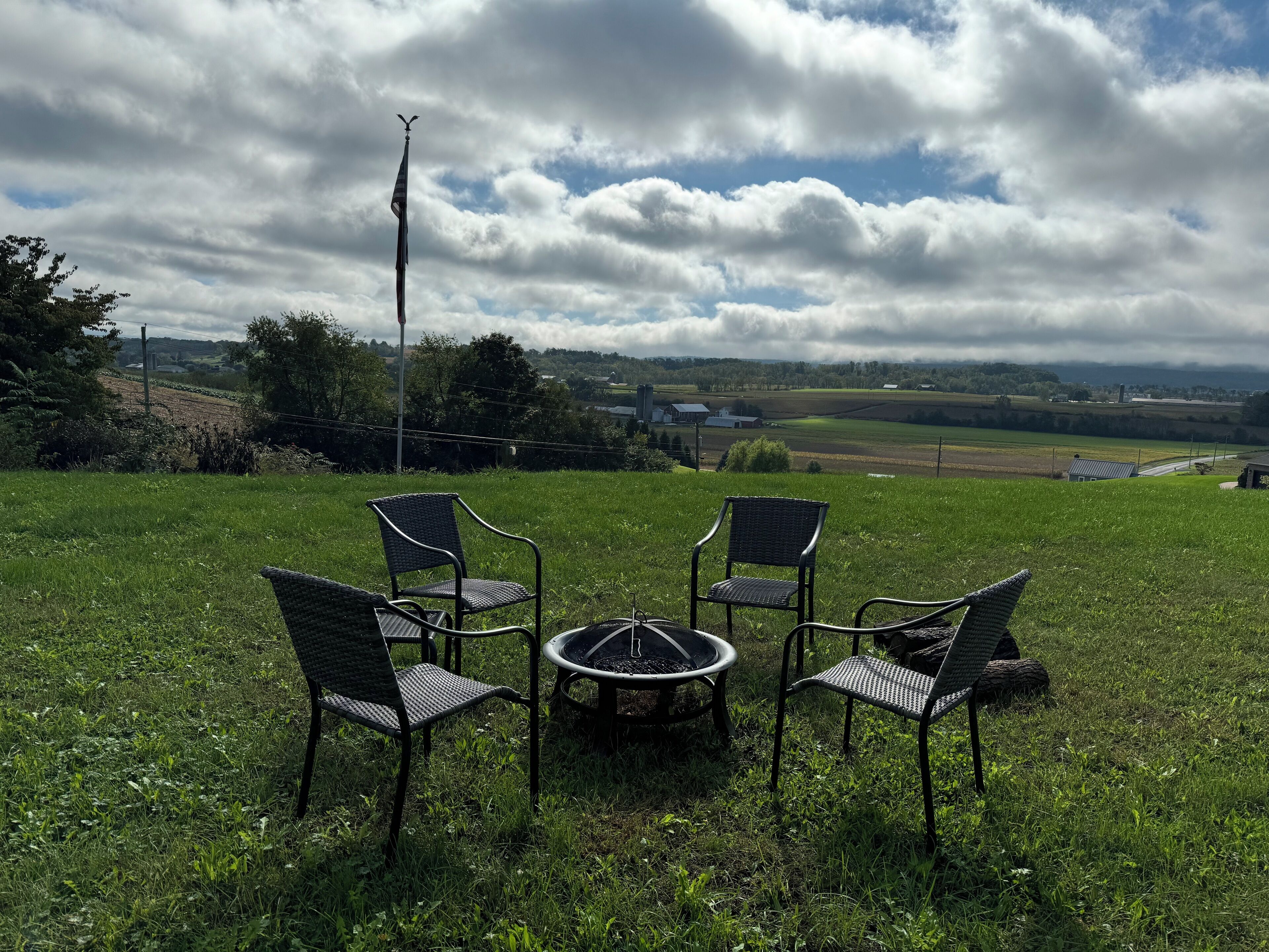 A grassy outdoor seating area with four chairs and a central fire pit.