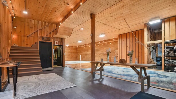 Un intérieur en bois avec une table centrale, un escalier et une vue sur l’extérieur.