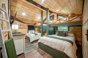 A cabin with two beds, a desk, and a ladder.