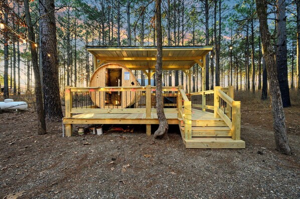 A wooden cabin with a covered porch and a staircase leading to a loft area.