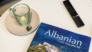 A book titled "Albanian Coast from the Air" and a remote control on a table.