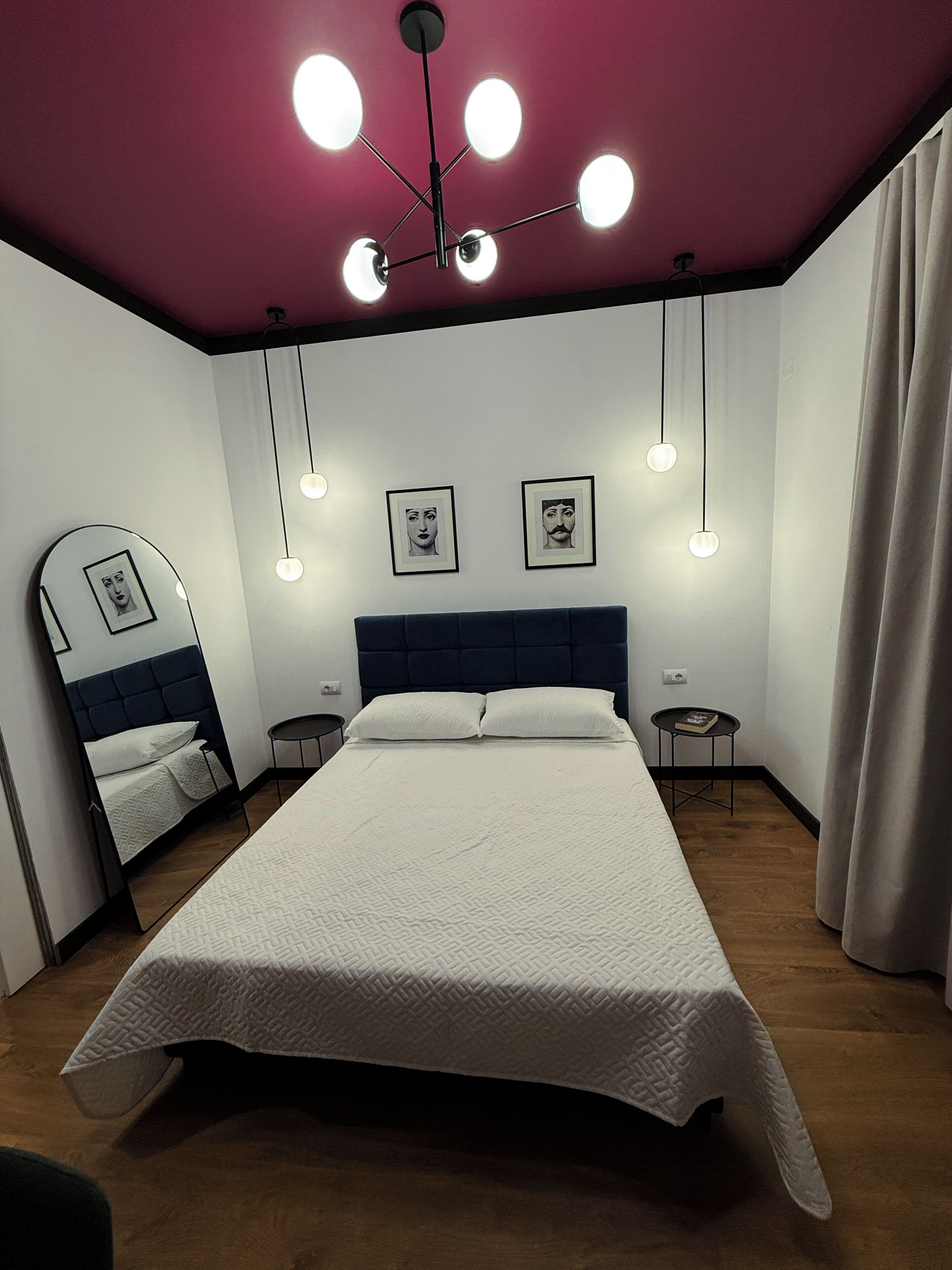 Une chambre à coucher comprenant un lit, des tables de chevet, un miroir et un luminaire au plafond.
