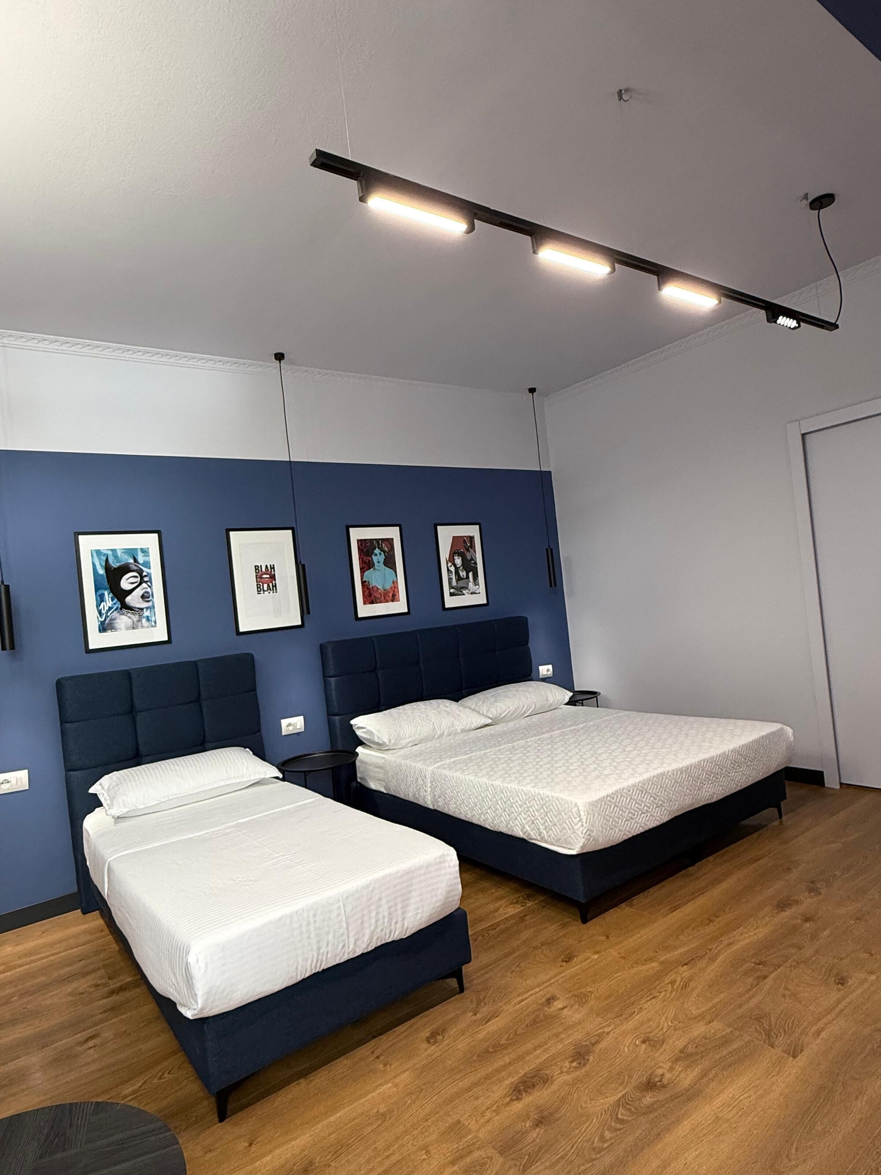 Un dormitorio moderno con dos camas, suelo de madera y una obra de arte en la pared.
