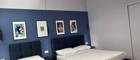 Un dormitorio moderno con dos camas, suelo de madera y una obra de arte en la pared.