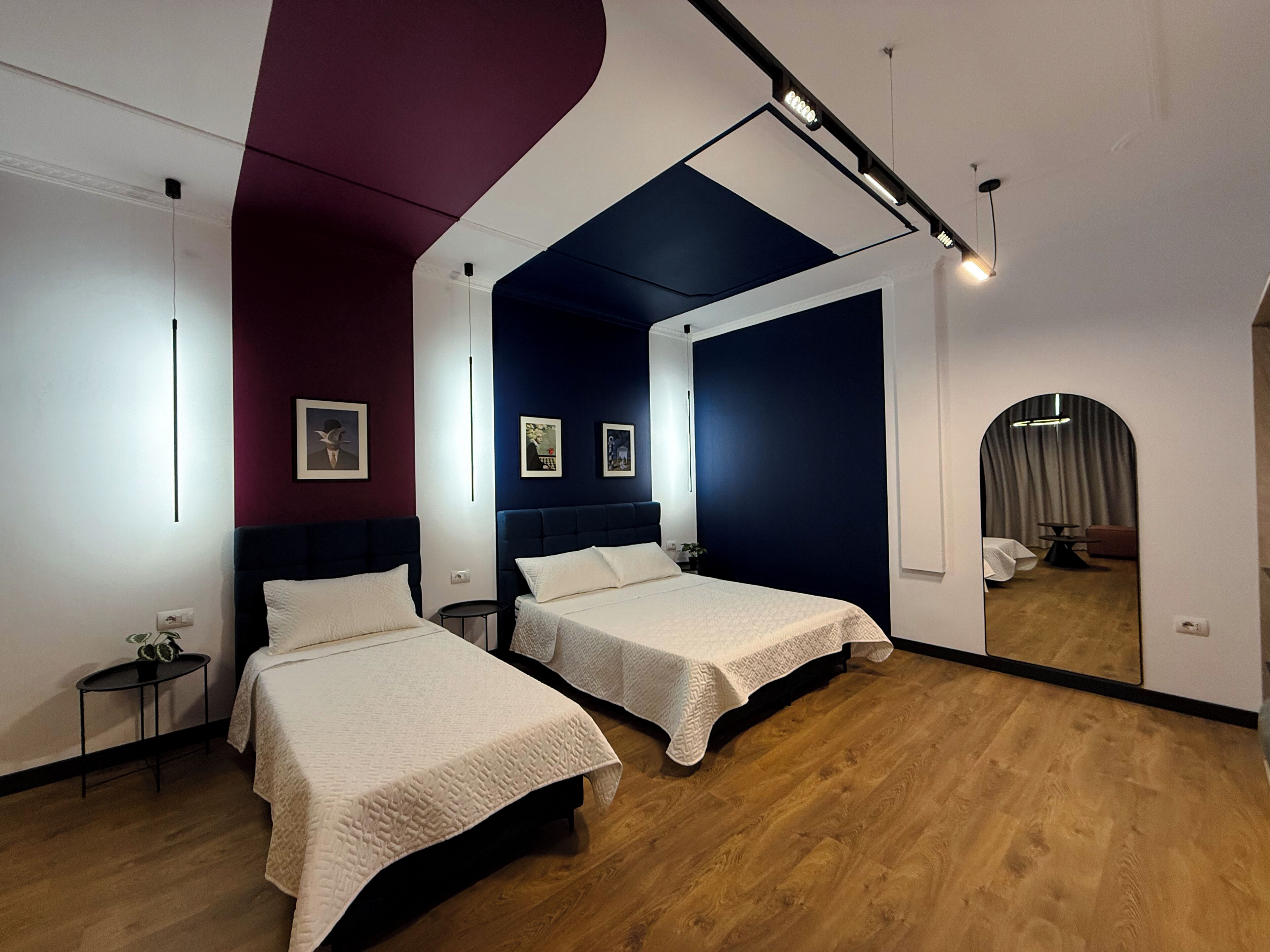 Une chambre moderne avec deux lits, un grand miroir et un plancher en bois.
