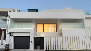 A modern two-story house with a garage, large windows, and a white picket fence. - Blue Lagoon duplex with views of cape blanc, sea 🌊, grotto beach and forest🌳 (Bizerte)