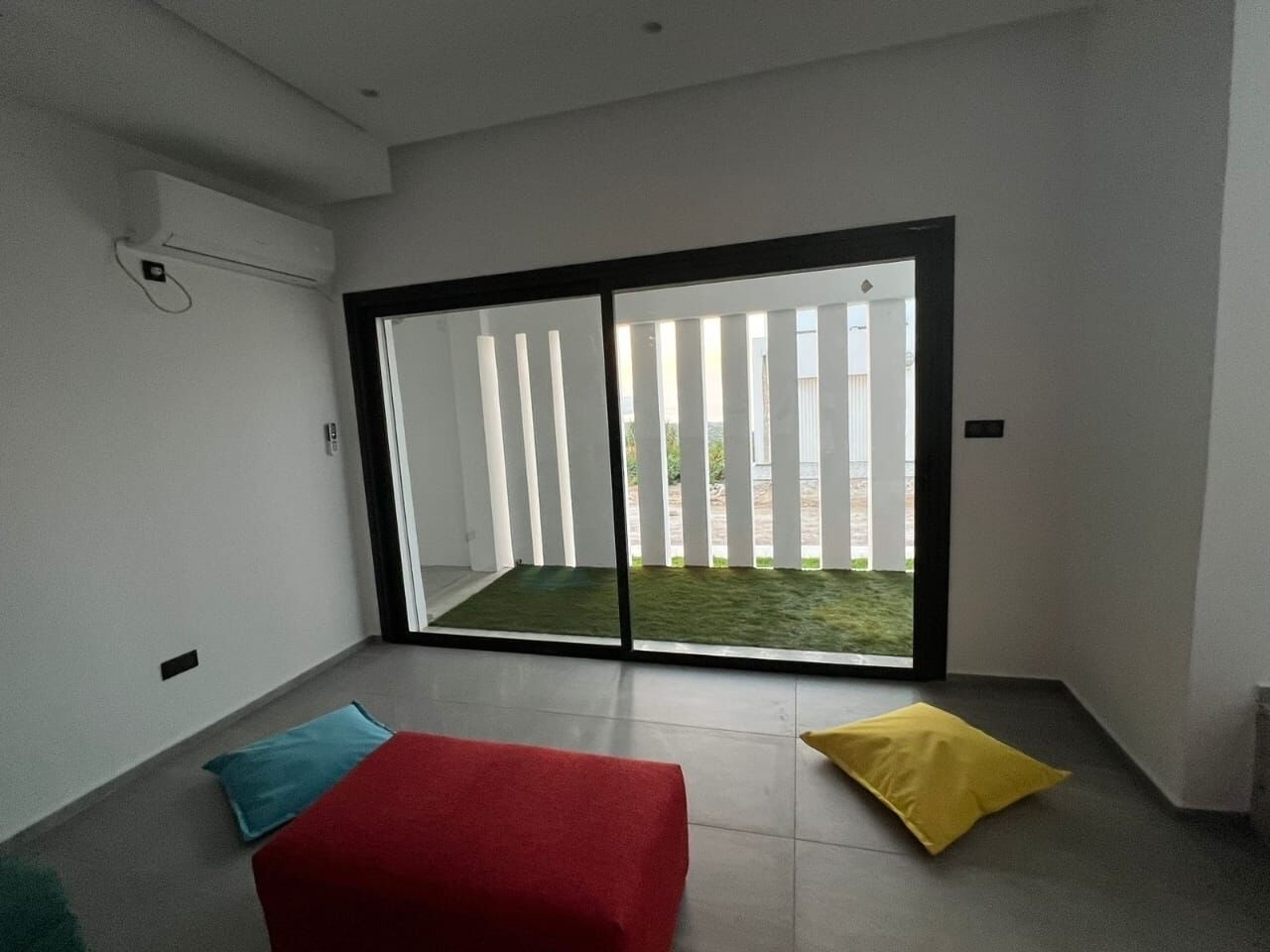 Ein Zimmer mit einer Schiebetür zu einem Balkon mit Blick auf eine Rasenfläche.