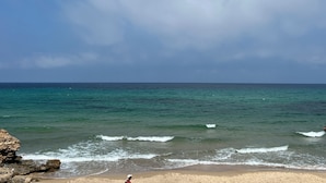 A beach with clear turquoise water and a rocky outcrop. - Blue Lagoon duplex with views of cape blanc, sea 🌊, grotto beach and forest🌳 (Bizerte)
