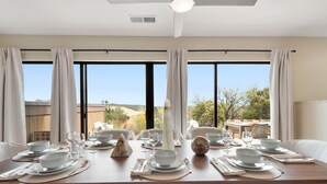 A dining area with a table set for four, large windows, and a view of the outdoors.