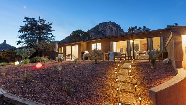 A modern house with a patio area, outdoor seating, and a view of a mountain.