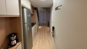A compact kitchen with a stainless steel refrigerator, a coffee maker, and a wooden countertop. - Beautiful studio with mezzanine in Brooklyn (Jardim das Acacias São Paulo)