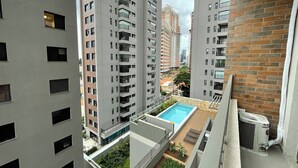 A high-rise residential building with multiple balconies, a rooftop pool, and a brick facade. - Beautiful studio with mezzanine in Brooklyn (Jardim das Acacias São Paulo)