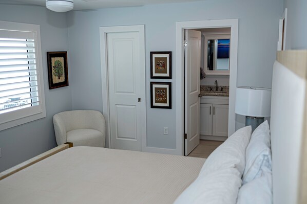 Une chambre à coucher comprenant un lit, une chaise et une porte donnant sur une salle de bain.