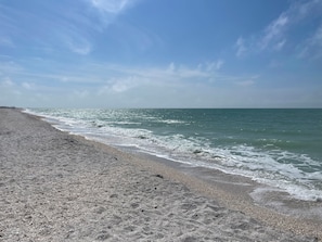 Une plage au rivage de galets, où les vagues viennent doucement lécher le sable.