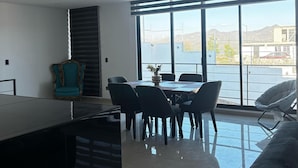 Una sala de estar moderna con comedor, ventanas amplias y vista a un cuerpo de agua.