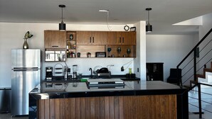 Una cocina moderna con armarios de madera, una isla central y un comedor con mesa y sillas.