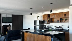 Una cocina moderna con una isla central, armarios de madera y electrodomésticos de acero inoxidable.