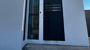 Un edificio moderno con fachada blanca, puerta negra y un gran ventanal.