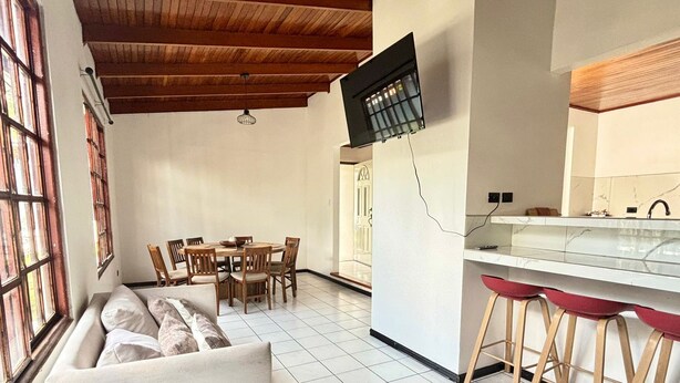 Et moderne køkken med spiseplads, sofa og bar med barstole.