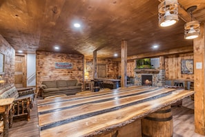 Een rustiek houten interieur met een lange bar, een zithoek en een stenen openhaard.