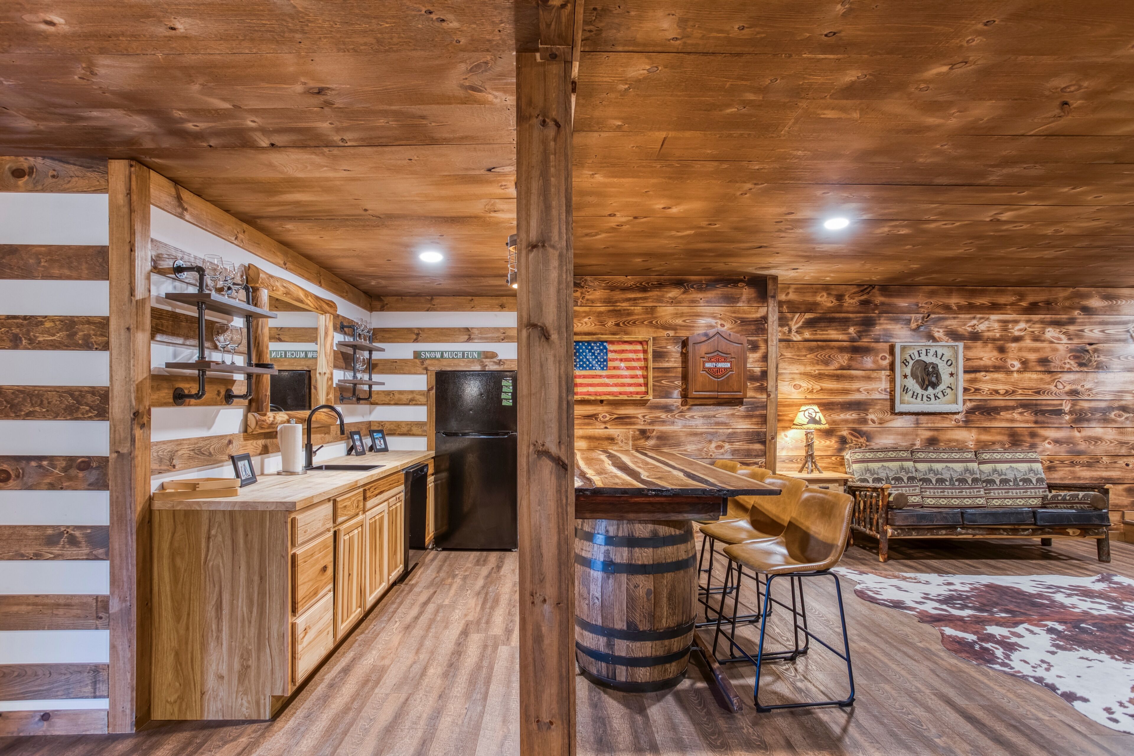 A rustic cabin interior with a kitchen, bar area, and seating space.