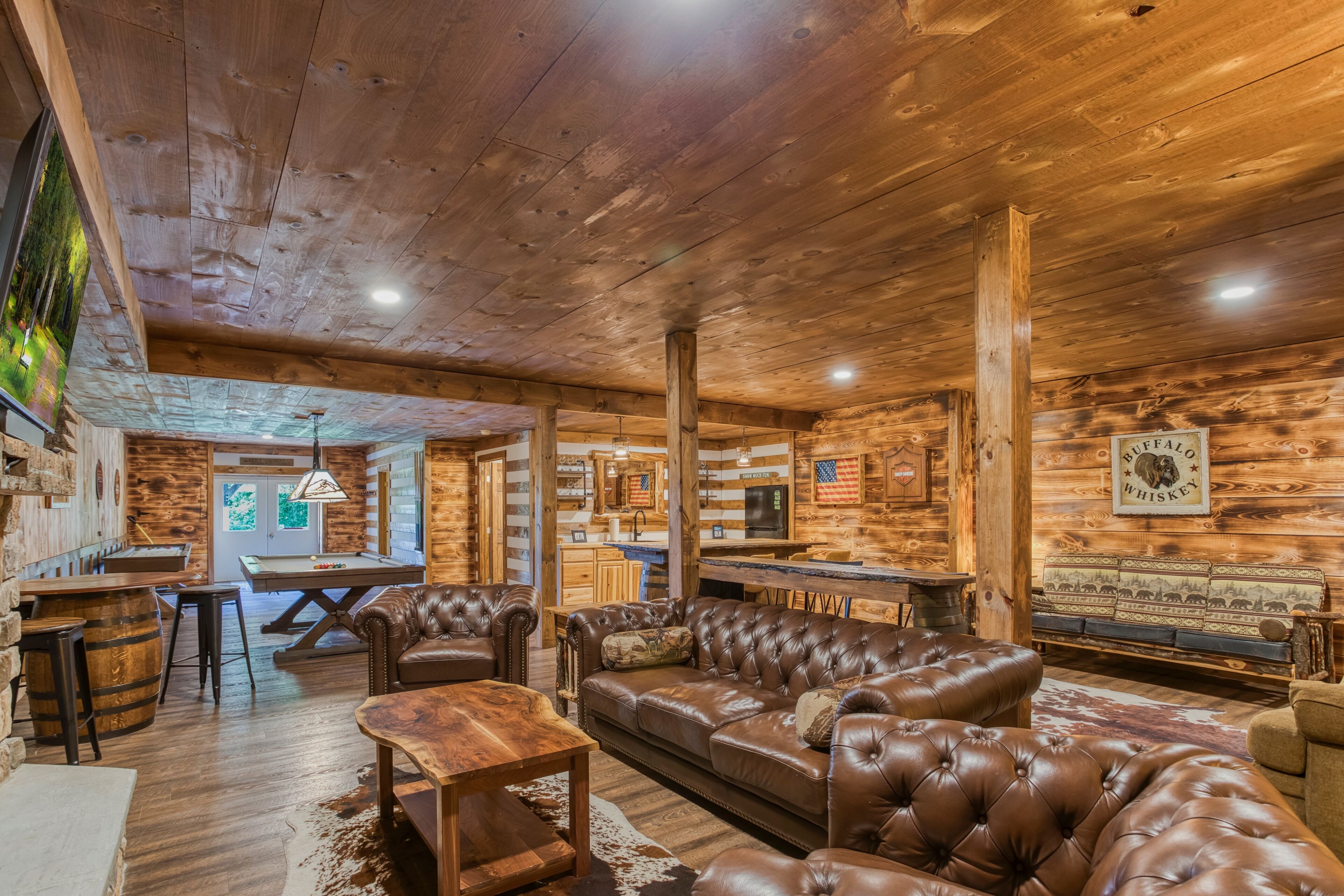 A rustic interior with a wooden ceiling, leather furniture, and a bar area.