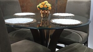 A dining table with four chairs, a vase with flowers, and a textured wall in the background. - Beautiful apartment in the center of Florianópolis (Centro Florianópolis)