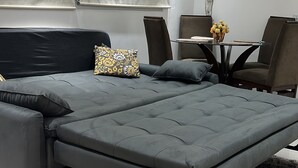 A modern bedroom with a large sectional bed, a small table with a vase of flowers, and a telephone on the wall. - Beautiful apartment in the center of Florianópolis (Centro Florianópolis)