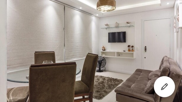 A modern living room with a sofa, chairs, a TV, and a decorative fan. - Beautiful apartment in the center of Florianópolis (Centro Florianópolis)
