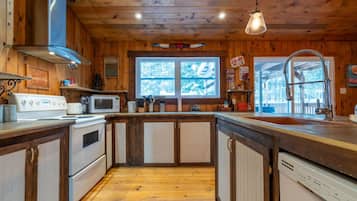 Kitchen features a central island, stainless steel range hood, microwave, and dishwasher, with a window offering a view of the outdoors.