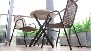 Un balcon avec des fauteuils en osier et une table ronde.