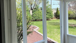 A covered porch with a view of a landscaped yard. - Welcome to the Moravian! (Allentown)