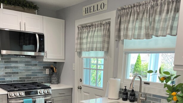A modern kitchen with white cabinets, stainless steel appliances, and a 'HELLO' sign above the door. - Welcome to the Moravian! (Allentown)