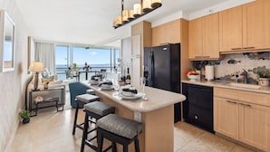 A modern kitchen with a central island, wooden cabinets, and a view to the outside.