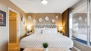 A modern hotel room with a large bed, a wooden bench, and a potted plant.