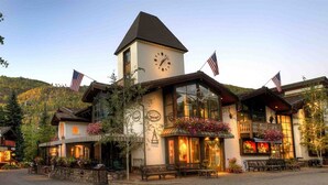 Un bâtiment doté d’une tour horlogée, orné de drapeaux américains, et abritant un restaurant avec une terrasse.