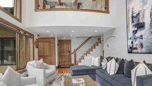 Un vaste espace de vie agrémenté d’un escalier en courbe, d’un grand tableau et d’un mélange de canapés et de fauteuils.