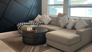 Una sala moderna con un sofá modular, una mesa de centro redonda y una alfombra estampada.