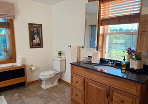 Un baño con inodoro, lavamanos, tocador y un cuadro en la pared.