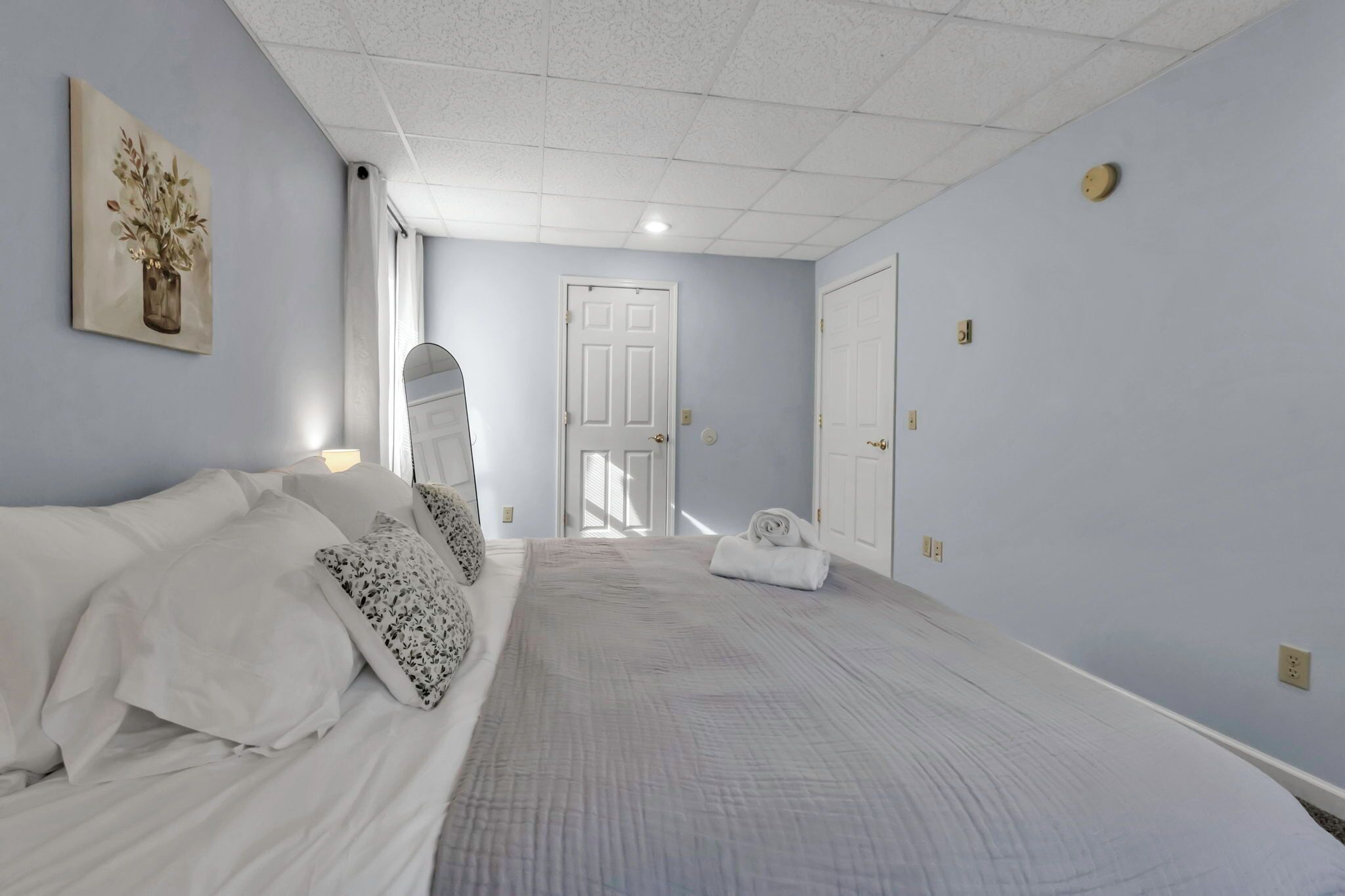 Een hotelkamer met een groot bed, een deur en een schilderij aan de muur.