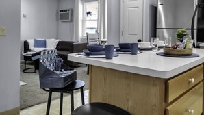 A modern kitchen with a central island, wooden cabinets, and a stainless steel refrigerator. - Suite Retreat: Cozy Walkable Akron Village Getaway (Akron)